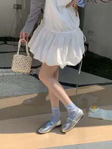 Nahaufnahme von silbernen Metallic Mary Jane Schuhen mit feinem Riemen und stylischen Socken.