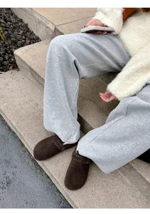 Detailaufnahme von braunen Wildleder Clogs kombiniert mit bequemen grauen Jogginghosen.