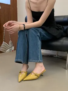 Scarpe mules eleganti a punta con tacco kitten in giallo, calzature estive da donna in dettaglio.