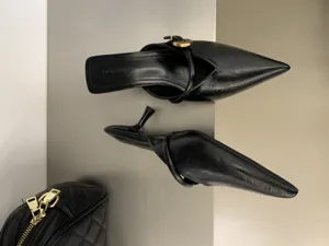 Mules slingback nere a punta con dettaglio di fibbia dorata e tacco kitten heel elegante.