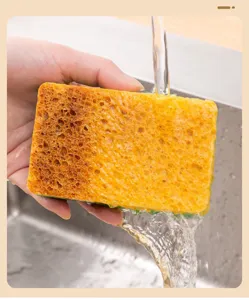 Wood pulp sponge detail showing porous texture and cleaning layer rinsed under water in sink.