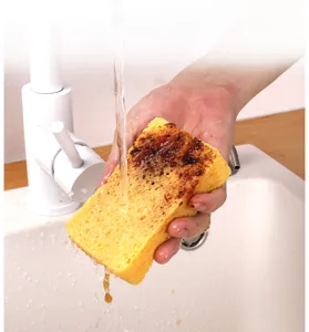 Detailaufnahme eines dicken Holzzelluloseschwamms unter fließendem Wasser zum Reinigen.