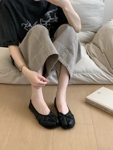 Close-up detail of women's black split-toe flat ballet shoes with sweet bow design, soft leather.