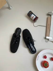 Mules negras tejidas con punta cuadrada para mujer con un detalle de lazo elegante.