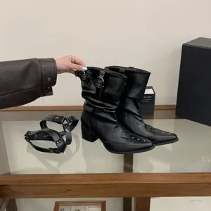 Gros plan de bottines occidentales noires à bout pointu, talons carrés et détails de clous.