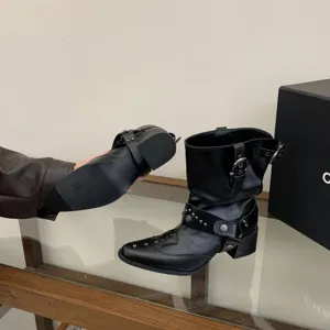 Vue détaillée de bottines western noires avec clous métalliques, talon bloc et belle boucle.