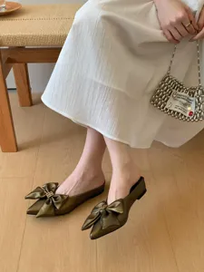 Elegante puntige mules met grote strik en metalen gesp voor een chique uitstraling.