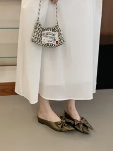 Detailopname van Franse elegante puntige muiltjes met strik en metalen gesp voor dames.