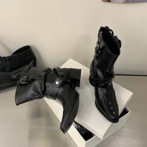 Vue détaillée de bottines western noires à bout pointu, talon épais et boucles en métal stylées.