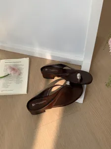 Brown leather thong sandals for women, minimalist flat mules with stylish metal ball decor.