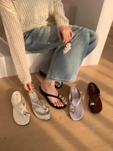 Detailed shot of minimalist thong sandals with metal ring accent and soft sole in multiple colors.