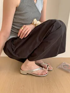 Close-up detail of women's silver metallic thong sandals with low heel and toe ring.