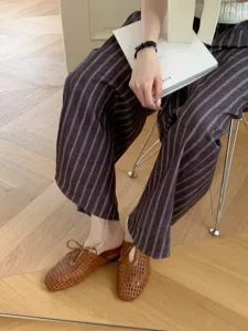 Primer plano de zuecos marrones de cuero trenzado con punta cuadrada y diseño de cordones.