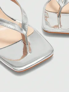 Close-up of silver metallic square toe thong high heels detail view, elegant party footwear design.