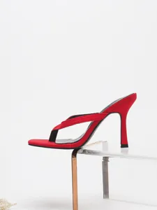 Detail shot of elegant red high-heeled thong sandals, featuring a sleek stiletto heel and strap.