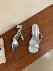 Détail de sandales argentées à talons hauts avec boucle métallique et talon bloc estivaux.