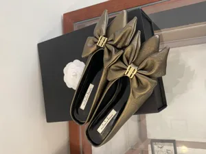 Details van bronzen metallic muiltjes met strik, elegante platte schoenen met gesp.