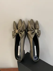 Metallische mules met puntige neus, grote stijlvolle strik en mooie metalen gesp.