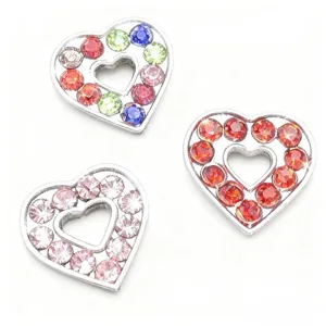 Dettaglio di ciondoli a cuore color argento decorati con strass colorati per progetti fai da te.