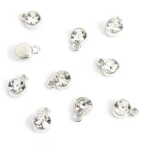 Gedetailleerde opname van kleine zilveren metalen bedels met heldere strass steentjes voor sieraden.