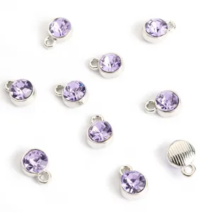Close-up van kleine lavendelkleurige strassbedels met zilveren lussen, perfect voor DIY-sieraden maken.