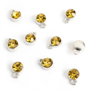 Detailopname van kleine gele strass bedels met zilveren oogje voor doe-het-zelf sieraden.