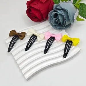 Satin bow hair clips detail view showing brown, white, pink and yellow variants on display.