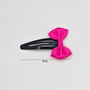 Detailed view of a cute hot pink ribbon bow hair clip on a black metallic snap hair pin.