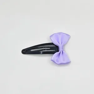 Detail view of a cute black BB hair clip decorated with a light purple ribbon bow for girls.