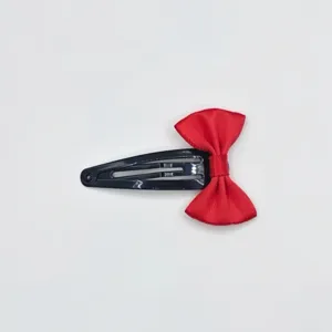 Detailed close-up view showing the exquisite red ribbon bow and black metal snap clip design.