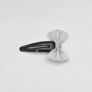 Close-up detail of a sweet silver satin bow hair clip, cute black metal snap clip for girls.