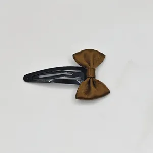 Detail view of the brown ribbon bow on a black metal snap hair clip close up shot.