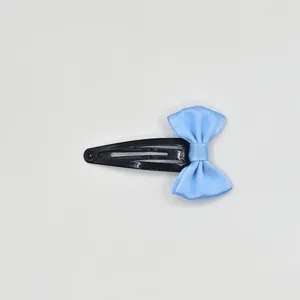 Detailed shot of a cute light blue ribbon bow attached to a black metal snap hair clip.