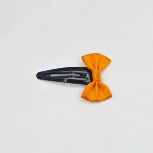 Orange satin bow detail on black metal snap hair clip, sweet girl hair accessory.