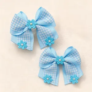 Close-up detail of blue gingham hair bow with pearl flower accent, cute hair accessory.