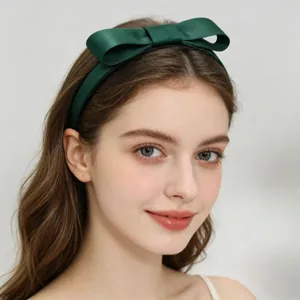 Close-up detail of dark green satin bow headband, elegant hair accessory for women & girls.