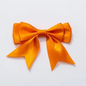 Oranje dubbellaagse zwaluwstaart lint strik detail, perfect voor kledingaccessoires en haarclips.