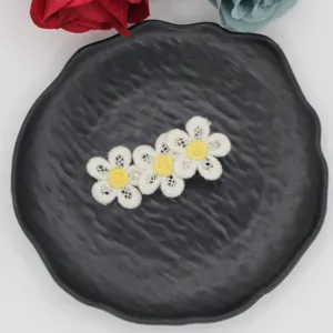 Close-up detail of cute embroidered daisy flower hair clip for kids, sweet floral design accessory.