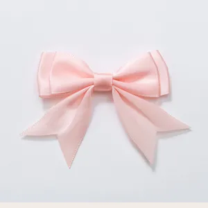 Close-up van het delicate roze satijnen dubbele zwaluwstaart strik haaraccessoire detail.