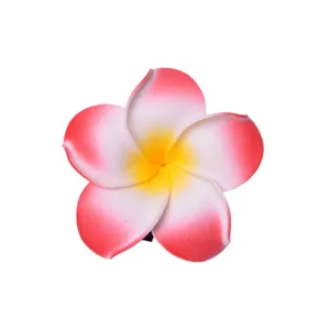 Primo piano della molletta per capelli con fiore di plumeria artificiale sfumato rosa e giallo.
