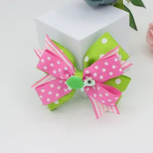 Detailed view of kids pink green polka dot hair bow clip with cute little turtle charm.