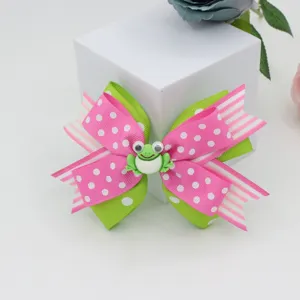 Close-up detail of cute pink polka dot bow hair clip with cute frog decoration for girls.