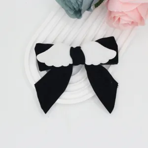 Sweet Lolita black velvet hair bow clip featuring cute plush angel wings, detailed closeup view.