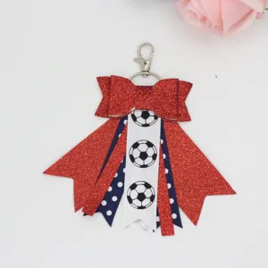 Red glitter bow keychain detail, soccer ball pattern bag charm, stylish chic accessory.