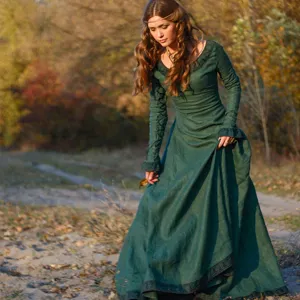 Vue détaillée de la robe longue médiévale vintage verte portée en extérieur sur un sentier.
