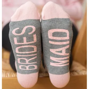 Detail view of grey and pink bridesmaid party socks featuring clear BRIDES text print.