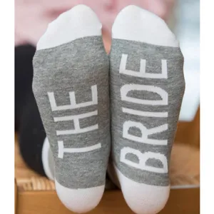 Close-up detail of wedding bride party socks showing white text on gray knit fabric sole.