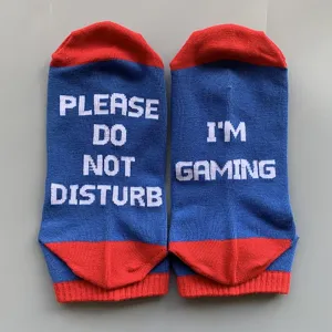 Close-up detail of blue and red cotton socks featuring humorous white woven gaming text.