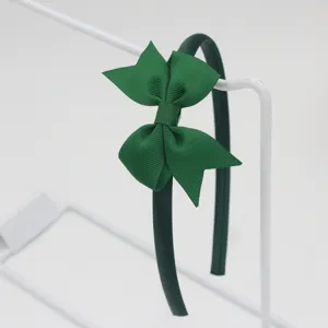 Vue détaillée du serre-tête nœud en ruban gros-grain vert foncé, accessoire élégant et simple.