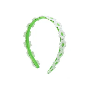 Detailed close-up of a sweet green headband decorated with lovely white daisy flowers.